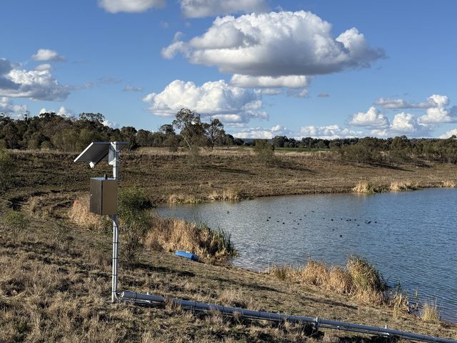 Solar-powered dam monitoring station on the bank of a dam, with its sensor line running to the water