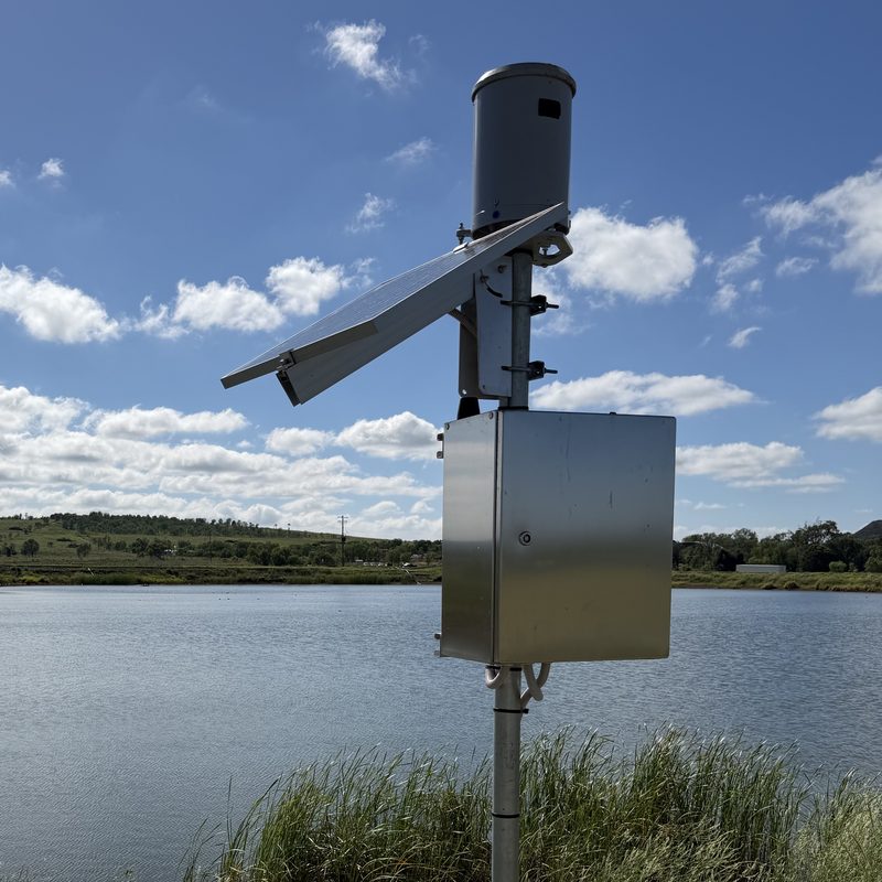 Hydsight dam monitoring station with solar panel, rain gauge and enclosure beside a dam